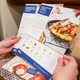 Hands holding a recipe card for Blue Apron's subscription meal kit